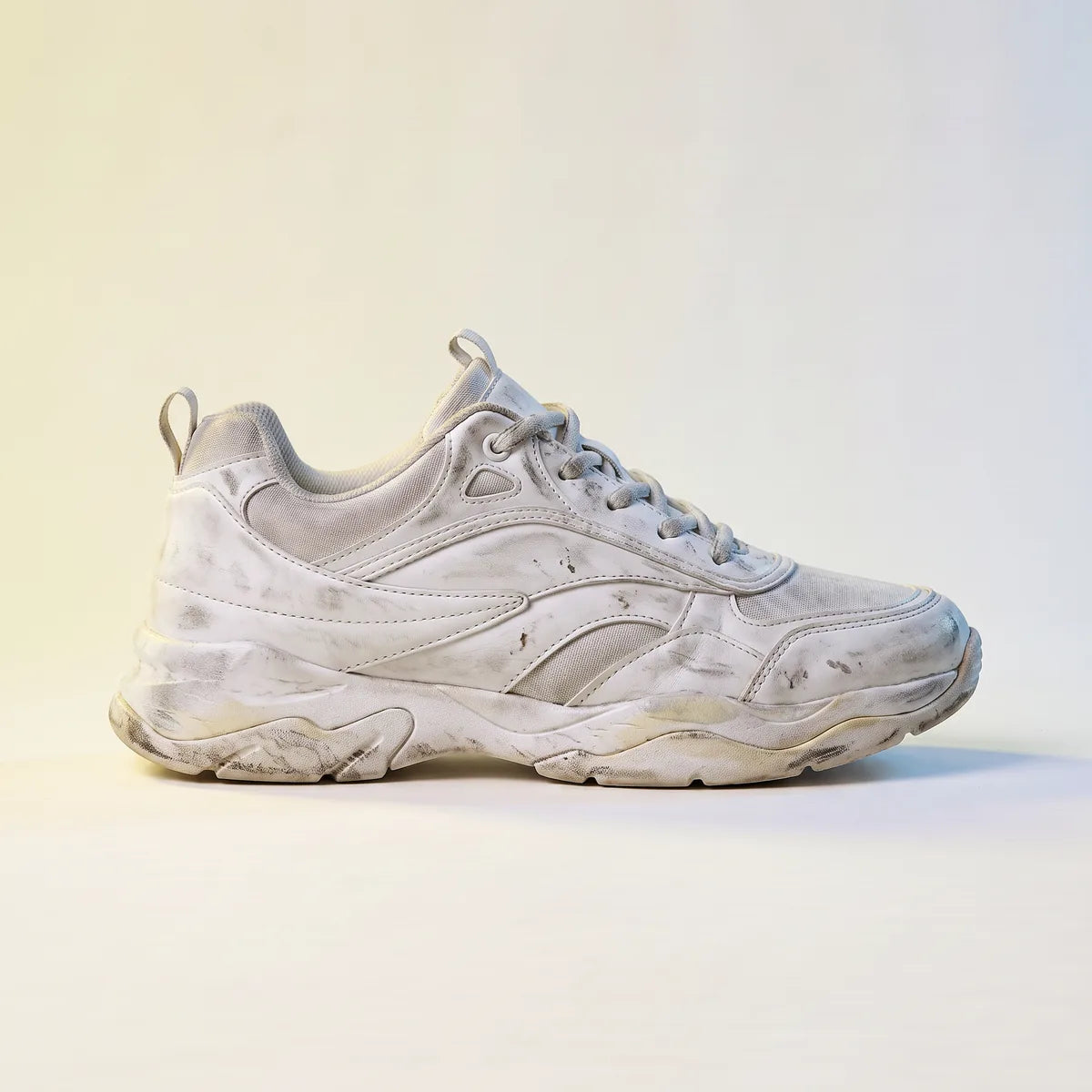 Sneaker blanche encrassée, de profil, avant le passage en machine