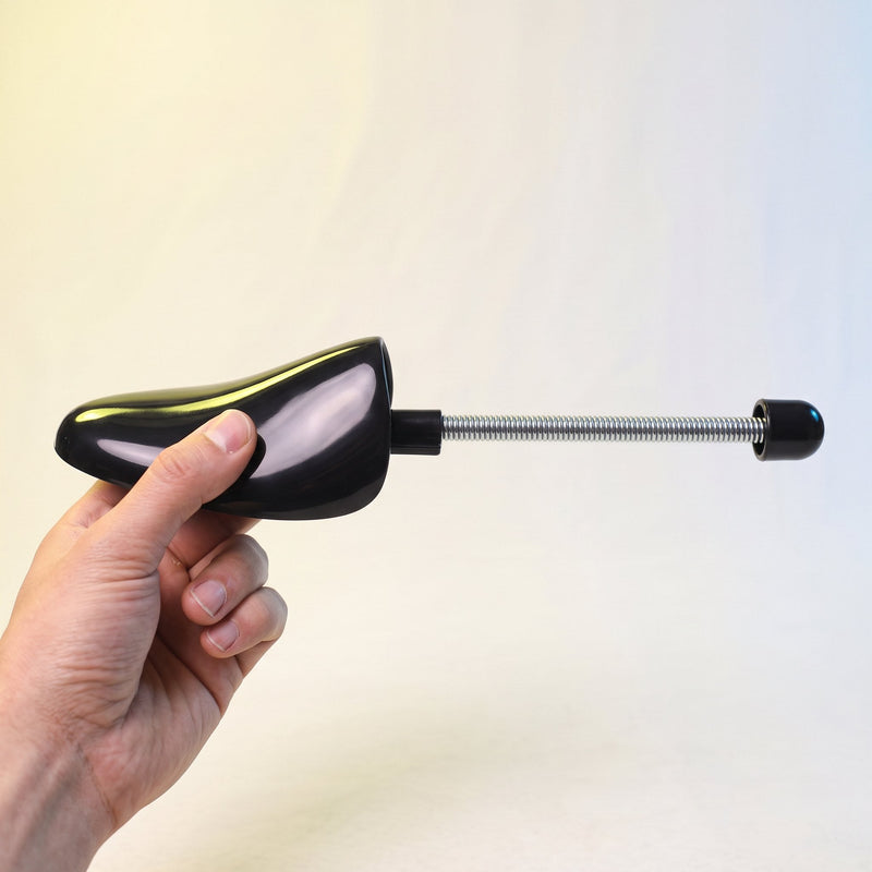 Embauchoir tenu par sa coque, la tige à ressort nettement plus longue que la main