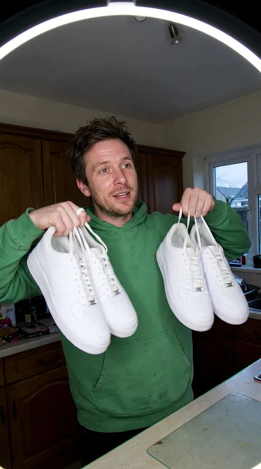 Deux paires de sneakers blanches propres tenues par les lacets